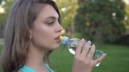 Woman Drinking Water From a Bottle Outdoors