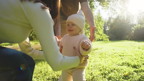 Father Encourages Toddler to Walk in Sunny Park During Autumn Afternoon