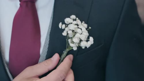 Man Puts on Boutonniere Flower on Wedding Day