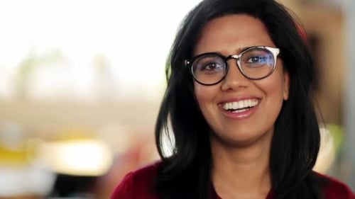 Smiling woman with glasses looks at camera