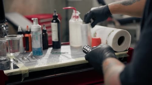Artist Preparing Tattoo Machine in Studio