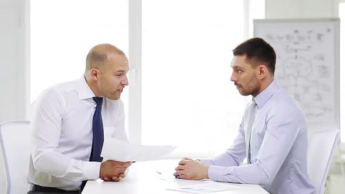 Serious businessmen discussing charts and documents in a modern office