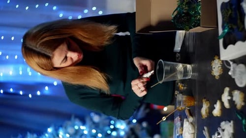 Woman Crafting Christmas Ornaments at Home at Night