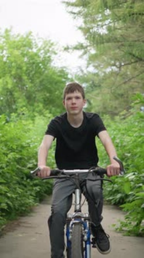 Young Boy Smiling While Cycling on Scenic Path Surrounded By Lush Greenery