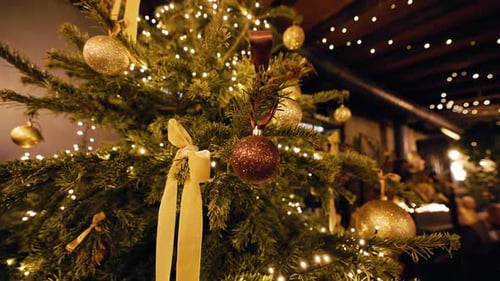 Un elegante árbol de Navidad adornado con adornos dorados y luces centelleantes crea un