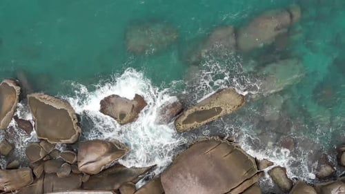 Aerial view of ocean waves crashing on rocks.