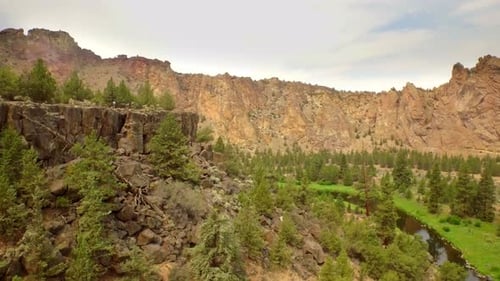 Aerial View of Person Walking Across Plateau Surrounded by Mountains and Forest