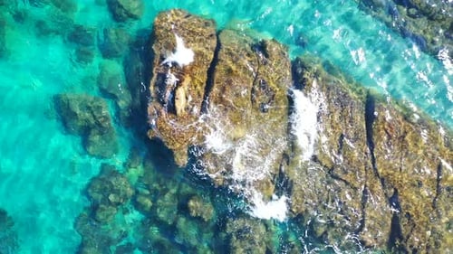 static shot of mediterranean sea with big rock breaking the surface of crystal clear water, interest