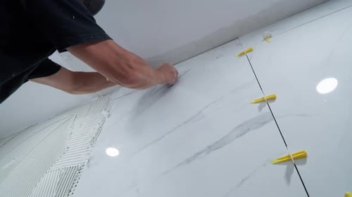 Tiler Working on Marble Wall in Bathroom