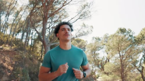 Young Man Jogging Through the Forest on Sunny Day