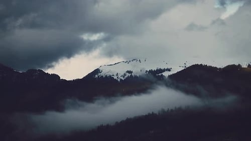 Ziehende Wolken und Nebel in Bergen mit Schnee