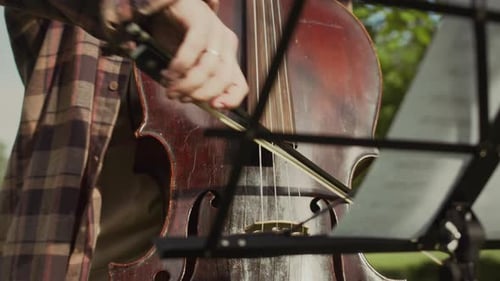 Musician Playing Cello by Sheet Music Stand Outdoors