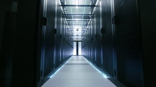 La caméra passe par des portes coulissantes qui s'ouvrent pour entrer dans un grand centre de données moderne. Rangées de serveurs rack fonctionnels