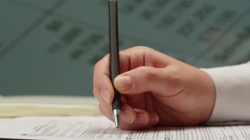 Close Up Hand Filling Out Form with Pen