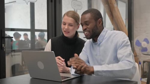 Colleagues Collaborating on Laptop in Modern Office