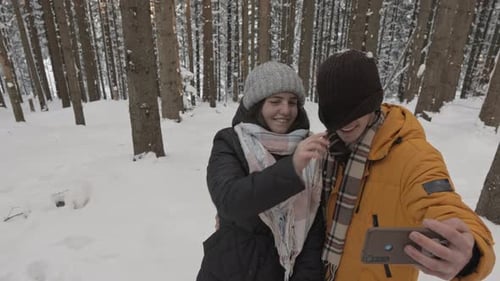Selfie parmi les arbres enneigés, un homme et une femme affirment leur affection l'un pour l'autre avec Open
