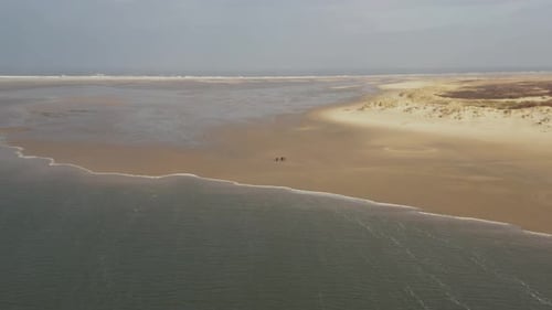 Dramatic drone aerial shot of a couple of people walking on an empty beach on frisian island Borkum