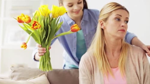 Girl gives flowers to her smiling mother