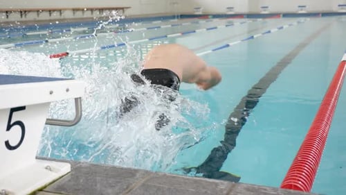 Chapoteando en la piscina, el nadador se da un gran chapuzón durante la práctica de natación