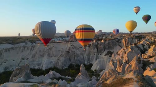 Colorful Hot Air Balloons Over Rocky Landscape at Sunrise