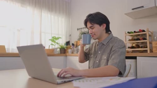 Man Working on Laptop with Coffee in Kitchen
