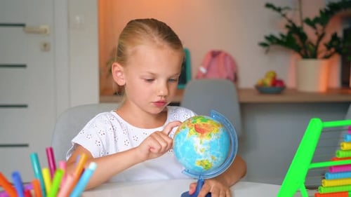 Child Studies Globe at Desk During Daytime