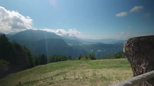 Expansive view of alpine mountains and lush green valleys under a clear blue sky, offering a tranqui