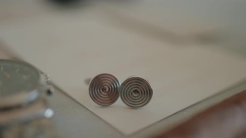 close up of spiral cufflinks with wristwatch in elegant groom accessory composition