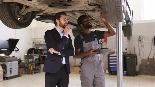 Mechaniker erklärt Geschäftsmann in der Autowerkstatt die Autoinspektion