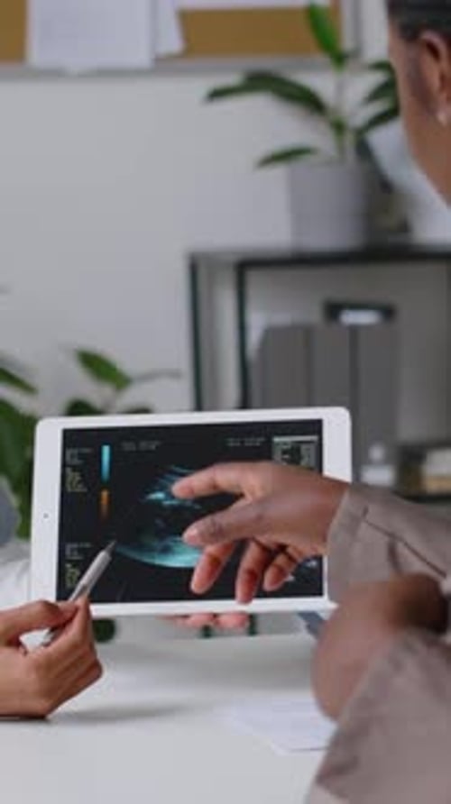 Main d'une obstétricienne montrant une échographie sur une tablette à une femme enceinte