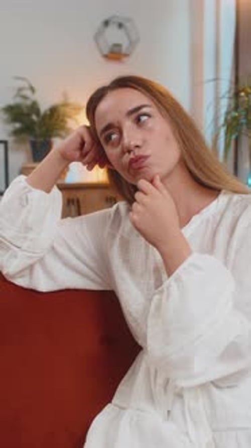 Thoughtful Woman Sitting on Couch Indoors