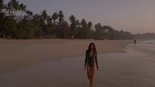 Elegant Woman Walking In Bodysuit On Tropical Beach In Morning Light