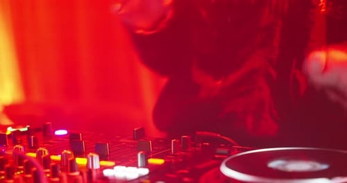 Nahaufnahme: DJ Hand passt den Fader an der digitalen Musikkonsole bei Neonlicht im Nachtclub an.