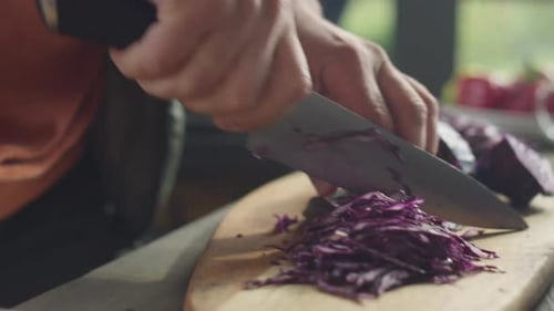 Hände des Chefkochs beim Zerkleinern von Rotkohl