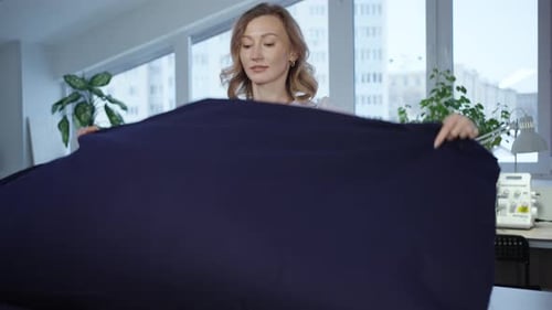 Woman Tailor Prepares Piece of Fabric for Cutting in Atelier