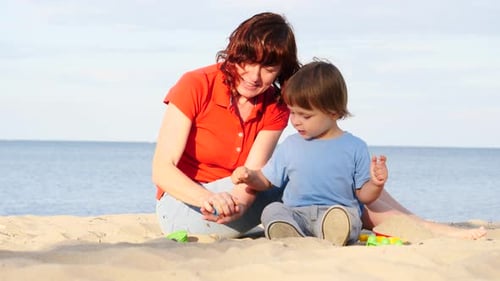 Madre juega con su hijo pequeño en la playa