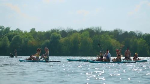 Happy People Floating On Paddleboard In River Swaying Hands To Camera Admiring Nature And Resting