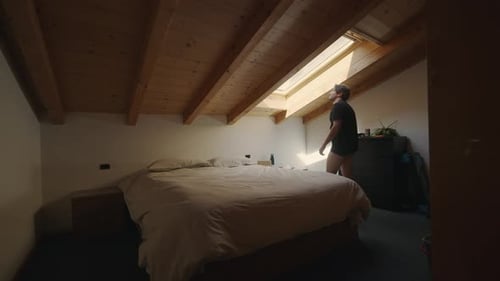 Man Sits Down on Bed in Bedroom
