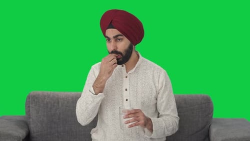 Sikh Indian man taking medicine Green screen