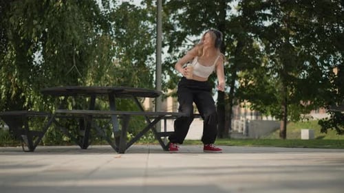 Woman Performs Freestyle Dance Near Park Bench with Concentration Woman Stretches and Ties Her Shoe