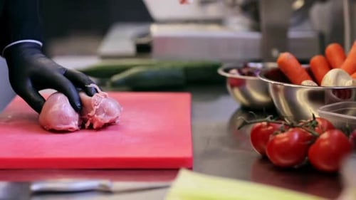 Chef prepares chicken breast with fresh vegetables