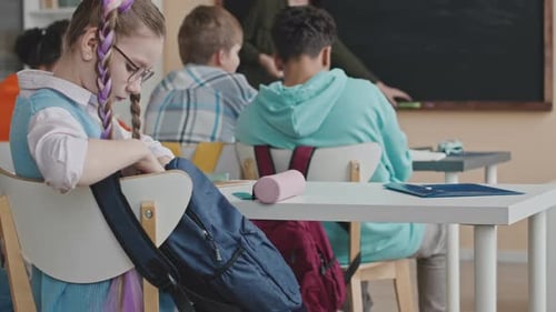 Schulmädchen holt während des Unterrichts Briefpapier aus der Tasche