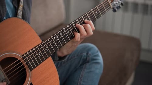 Closeup of a Man Playing an Acoustic Guitar The Frame Shows the Fretboard and the Musician's Hand
