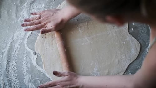 Frau knetet Teig auf bemehlter Oberfläche