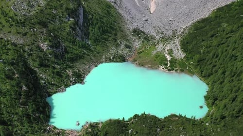 Lake Sorapis bright turqoise water in the Dolomites Italy, tilt down aerial