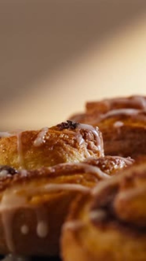 Vertical - Freshly-baked Cinnamon Rolls Drizzled With Sugar Glaze. close-up, rotating shot