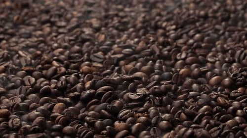 Roasted coffee beans. The smoke comes from fresh coffee seeds.