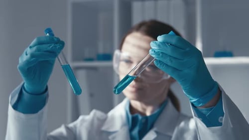 Un scientifique hautement qualifié analyse des solutions chimiques dans des tubes à essai étiquetés essentiels pour