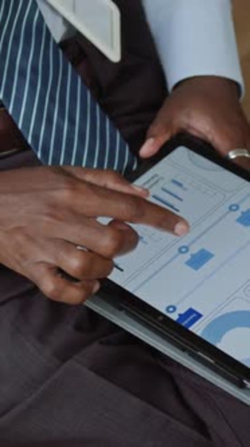 Businessman Scrolling through Graphic Data on Tablet Screen at Seminar
