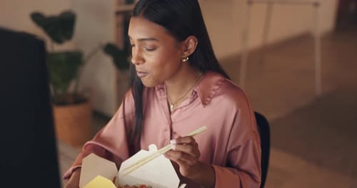 Woman Eating Food at Computer in Office